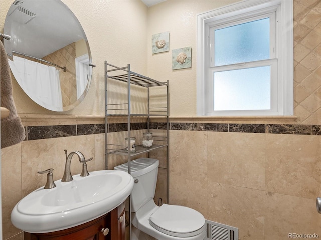 bathroom with tile walls, toilet, vanity, and a shower with curtain