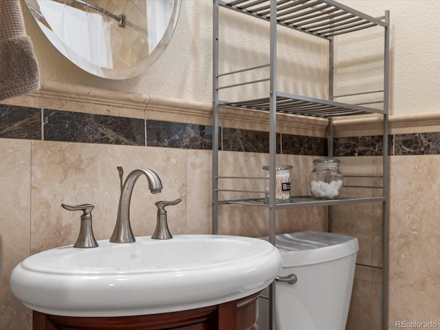 bathroom with sink, tile walls, and toilet