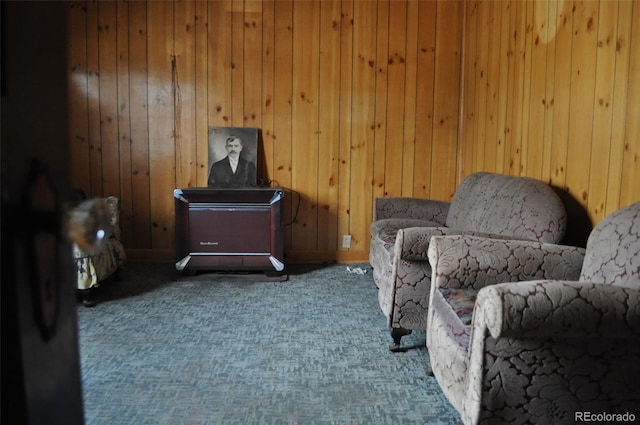 living area featuring wood walls and carpet flooring