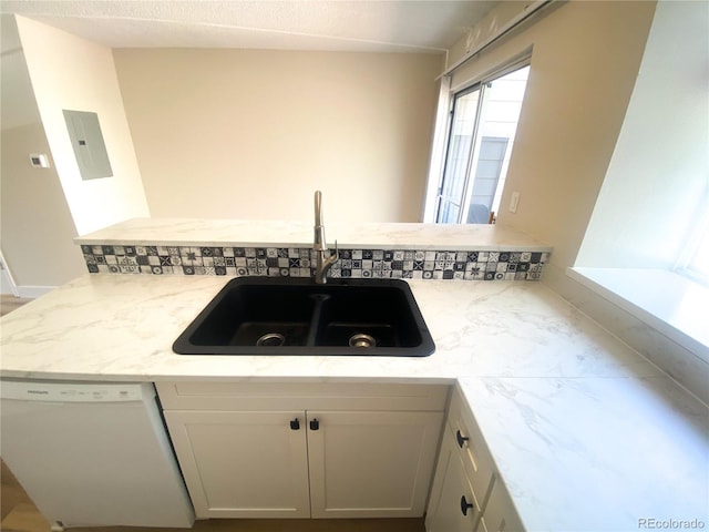 kitchen featuring dishwasher, kitchen peninsula, sink, white cabinets, and light stone counters