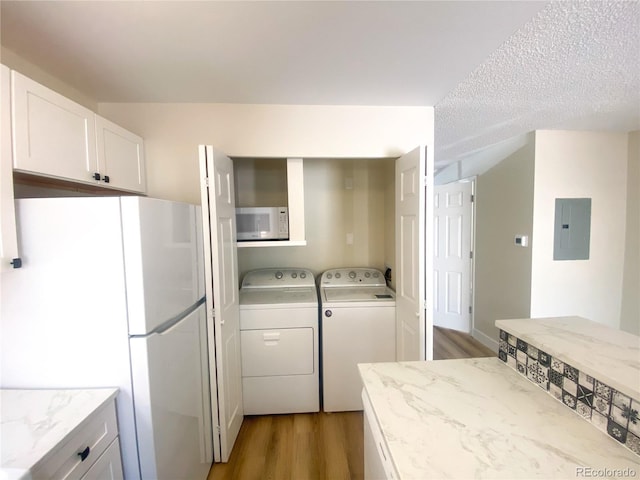 kitchen with electric panel, white appliances, light hardwood / wood-style flooring, separate washer and dryer, and white cabinets