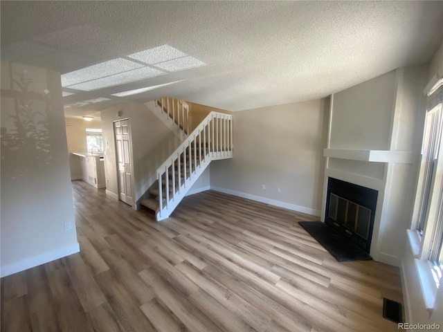 unfurnished living room featuring hardwood / wood-style flooring and a textured ceiling