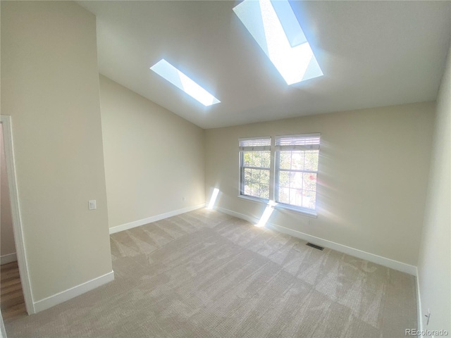 carpeted spare room with lofted ceiling with skylight