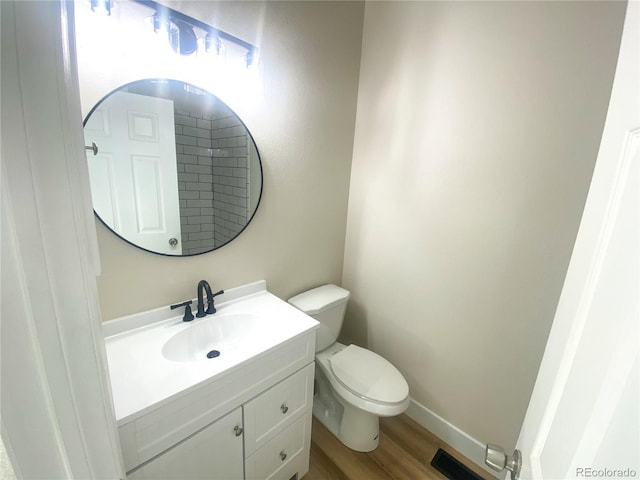 bathroom featuring toilet, vanity, and wood-type flooring