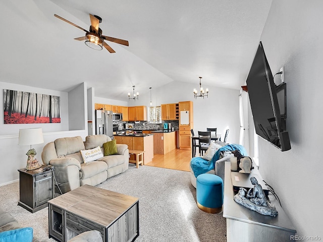 living room with ceiling fan with notable chandelier and vaulted ceiling