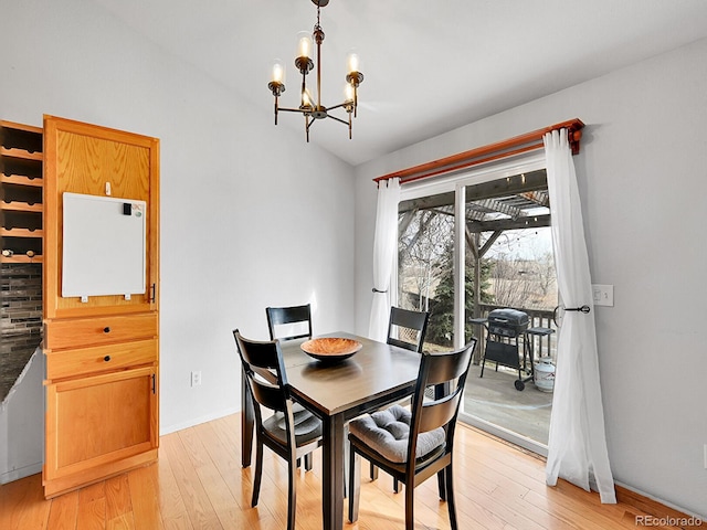 dining area with a notable chandelier, baseboards, light wood-type flooring, and lofted ceiling