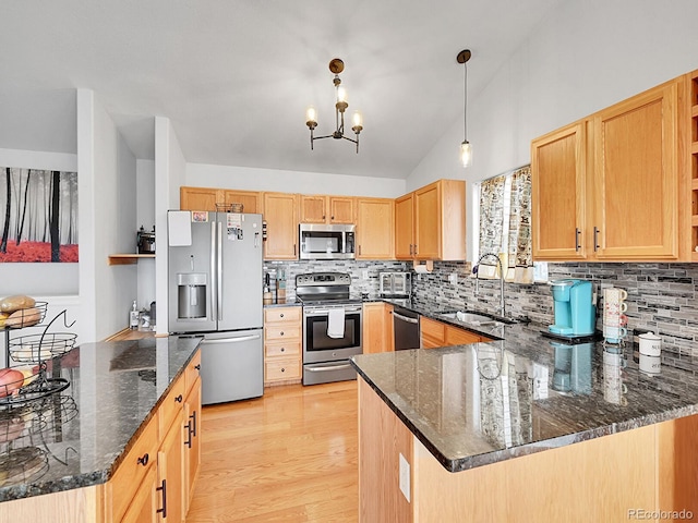 kitchen with light brown cabinetry, light wood-type flooring, lofted ceiling, appliances with stainless steel finishes, and a sink