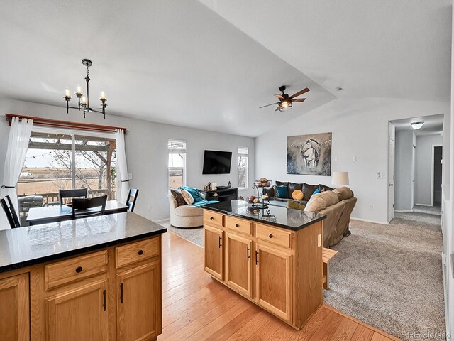 kitchen featuring light wood finished floors, lofted ceiling, open floor plan, and ceiling fan with notable chandelier