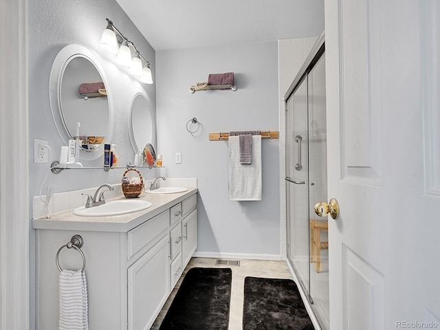 bathroom with double vanity, visible vents, a stall shower, and a sink