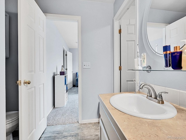 bathroom featuring toilet, vanity, and baseboards