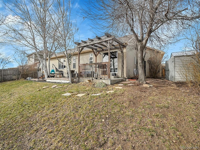 rear view of property featuring a deck, a yard, fence, and a pergola