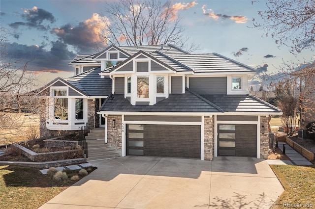 view of front of home with concrete driveway, an attached garage, and stone siding