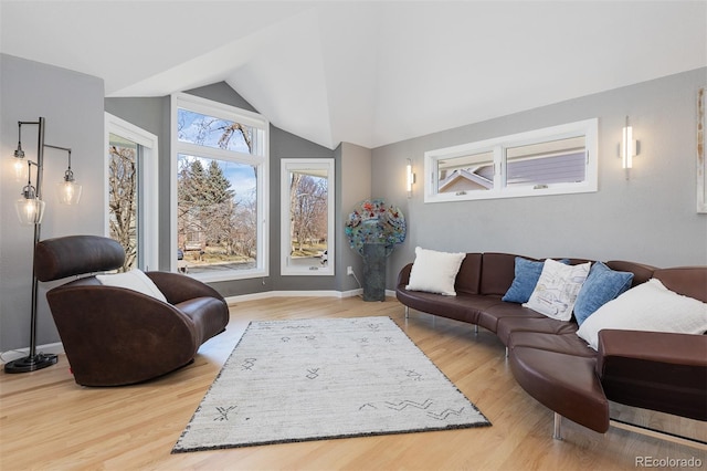 living area with vaulted ceiling, baseboards, and light wood-type flooring