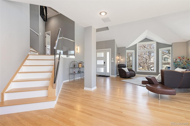 foyer entrance with baseboards, wood finished floors, stairs, and vaulted ceiling