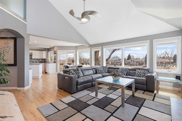 living room with a wealth of natural light, baseboards, light wood-style floors, and high vaulted ceiling