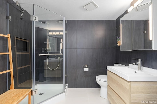 full bathroom featuring toilet, tile walls, a stall shower, and vanity