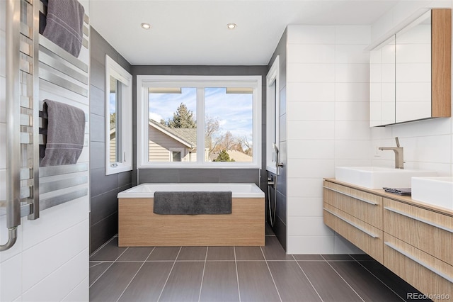 full bath with vanity, recessed lighting, tile walls, tile patterned floors, and a washtub