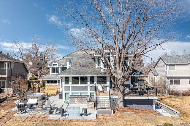 rear view of property with a sunroom, a fire pit, a deck, and a patio area