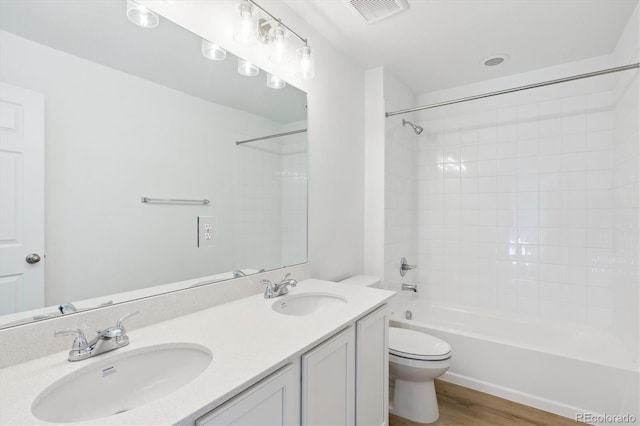 full bathroom with hardwood / wood-style floors, vanity, toilet, and tiled shower / bath combo