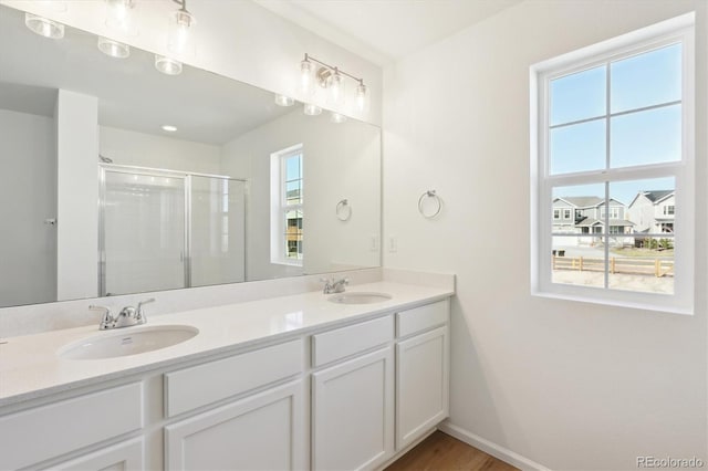 bathroom with hardwood / wood-style floors, a healthy amount of sunlight, an enclosed shower, and vanity