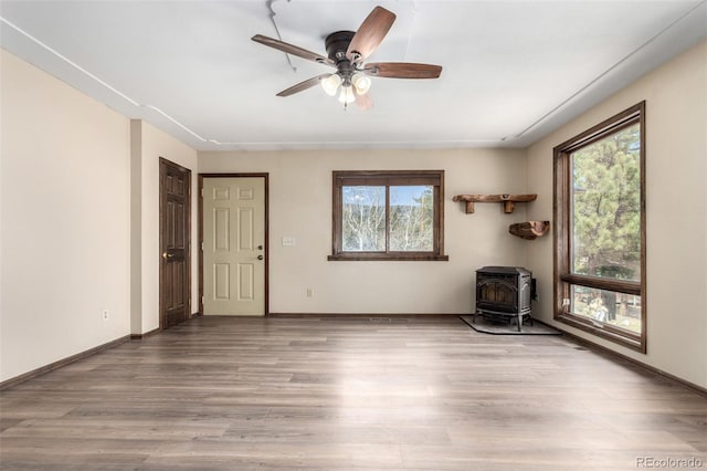 116 Schooley Rd, Bailey, CO 80421 - unfurnished room with a wood stove, healthy amount of natural light, wood finished floors, and ceiling fan