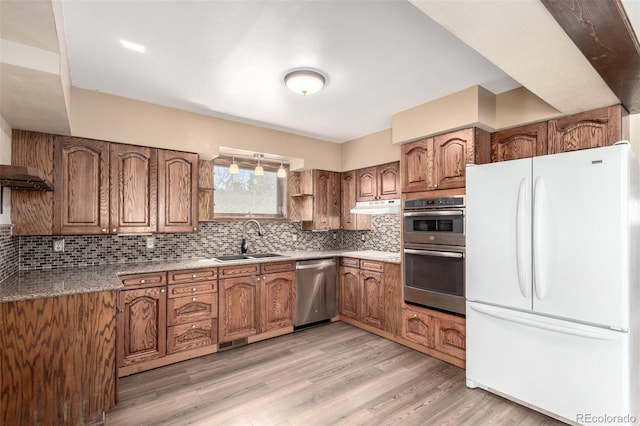 116 Schooley Rd, Bailey, CO 80421 - kitchen featuring appliances with stainless steel finishes, brown cabinetry, under cabinet range hood, backsplash, and light wood-style flooring
