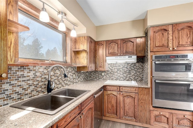 116 Schooley Rd, Bailey, CO 80421 - kitchen with appliances with stainless steel finishes, under cabinet range hood, brown cabinetry, and tasteful backsplash