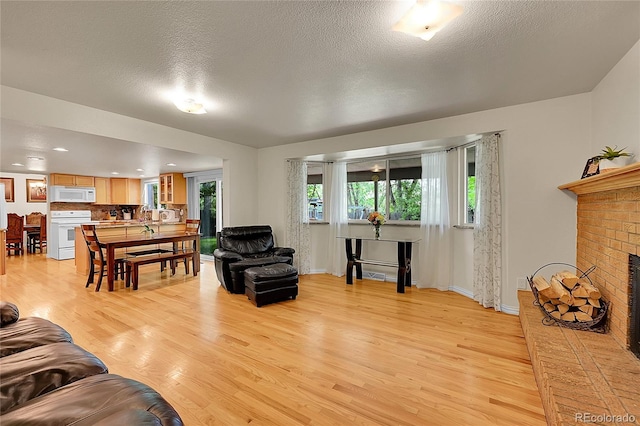 7439 S Depew St, Littleton, CO 80128 - living room featuring light wood-style flooring, recessed lighting, a fireplace, a textured ceiling, and baseboards