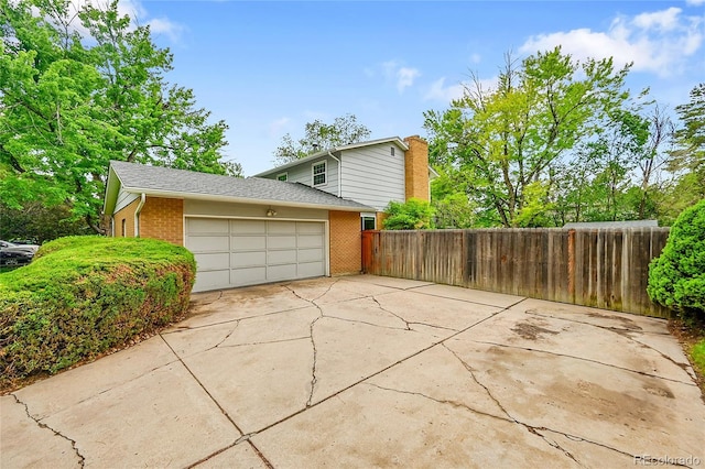 7439 S Depew St, Littleton, CO 80128 - view of home's exterior featuring brick siding, an attached garage, concrete driveway, and a chimney
