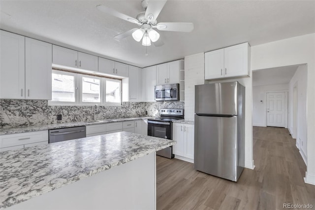 kitchen with white cabinetry, appliances with stainless steel finishes, light hardwood / wood-style floors, and decorative backsplash