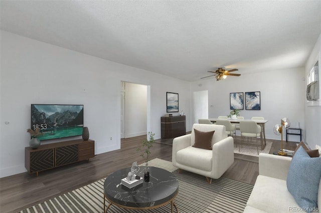 living room with dark wood-type flooring, ceiling fan, and a textured ceiling