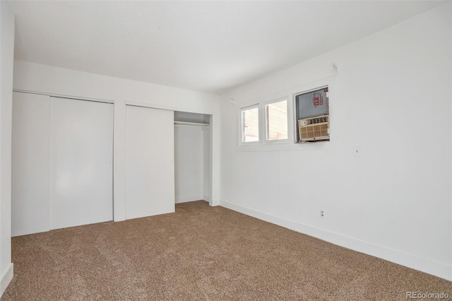 unfurnished bedroom featuring cooling unit, carpet floors, and multiple closets