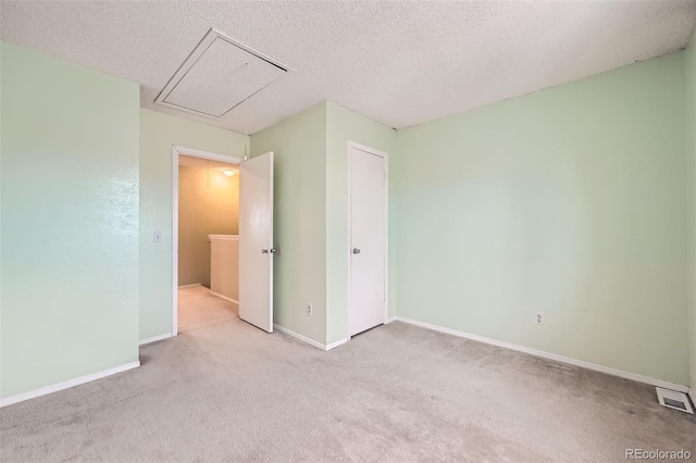 unfurnished bedroom with light colored carpet and a textured ceiling