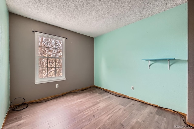 unfurnished room featuring a textured ceiling and light hardwood / wood-style flooring