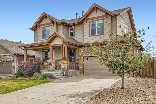 350 N Langdale Ct, Aurora, CO 80018 - view of front facade featuring an attached garage, a porch, driveway, fence, and stone siding