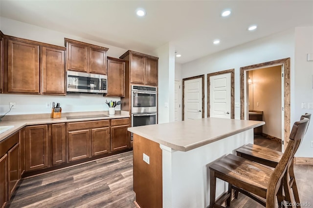 350 N Langdale Ct, Aurora, CO 80018 - kitchen featuring appliances with stainless steel finishes, dark wood finished floors, a kitchen bar, recessed lighting, and a center island