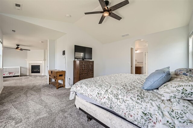 350 N Langdale Ct, Aurora, CO 80018 - carpeted bedroom featuring arched walkways, lofted ceiling, a tiled fireplace, and a ceiling fan