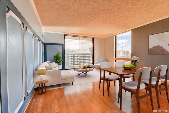 dining space featuring plenty of natural light, light wood-style flooring, a wall of windows, and crown molding