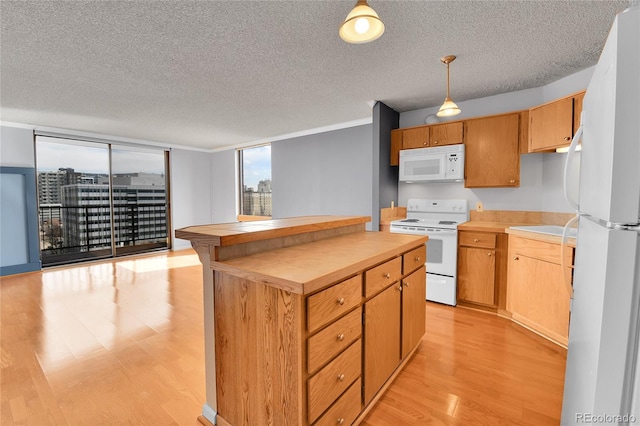 kitchen featuring a textured ceiling, white appliances, light wood-style floors, light countertops, and hanging light fixtures