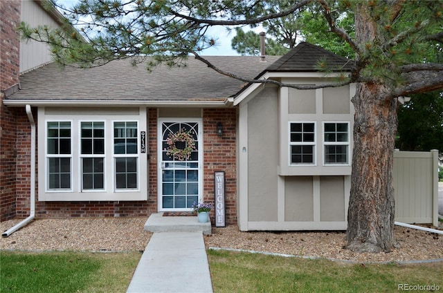9713 W Chatfield Ave Unit H, Littleton, CO 80128 - property entrance featuring roof with shingles, stucco siding, and brick siding