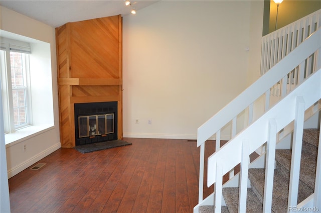 9713 W Chatfield Ave Unit H, Littleton, CO 80128 - unfurnished living room featuring healthy amount of natural light, dark wood-type flooring, stairway, and a large fireplace