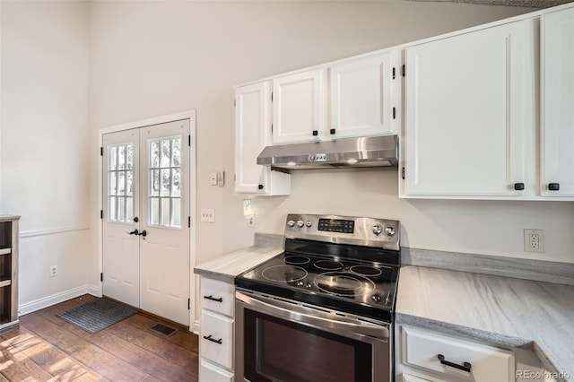 9713 W Chatfield Ave Unit H, Littleton, CO 80128 - kitchen with electric stove, under cabinet range hood, white cabinetry, and wood finished floors