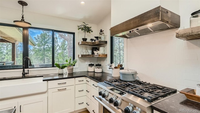 2231 Meadow Green Cir, Franktown, CO 80116 - kitchen featuring wall chimney range hood, stainless steel gas stove, open shelves, pendant lighting, and white cabinetry