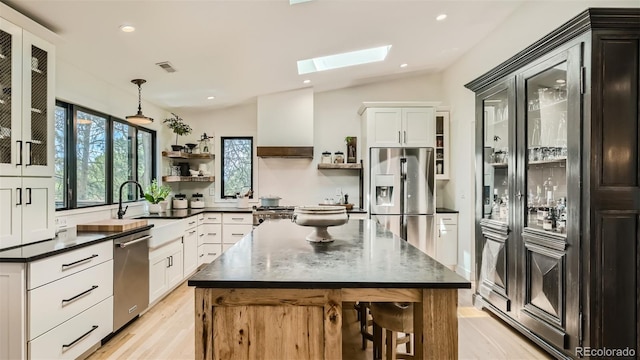 2231 Meadow Green Cir, Franktown, CO 80116 - kitchen featuring open shelves, stainless steel appliances, a skylight, light wood-style floors, and a kitchen island
