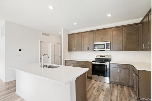 13412 E 110th Way, Commerce City, CO 80022 - kitchen with appliances with stainless steel finishes, light wood-type flooring, an island with sink, light countertops, and recessed lighting