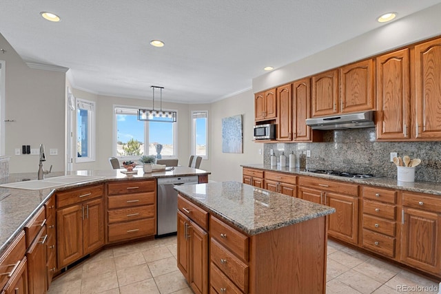 kitchen with stainless steel appliances, crown molding, sink, a kitchen island, and hanging light fixtures