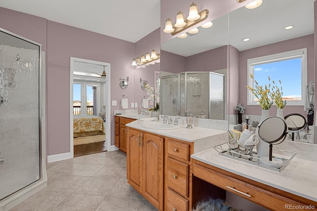 ensuite bathroom with ensuite bathroom, a stall shower, vanity, tile patterned flooring, and baseboards