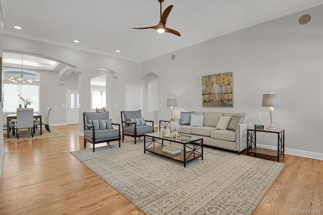 living room featuring ceiling fan with notable chandelier, crown molding, and light hardwood / wood-style flooring