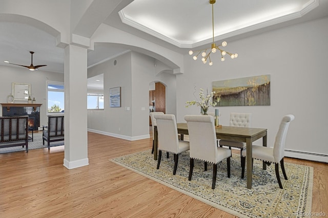 dining room with a baseboard heating unit, ornamental molding, ceiling fan with notable chandelier, and light wood-type flooring