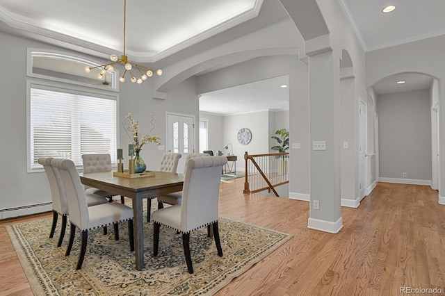 dining area featuring light wood-type flooring, a baseboard radiator, and crown molding